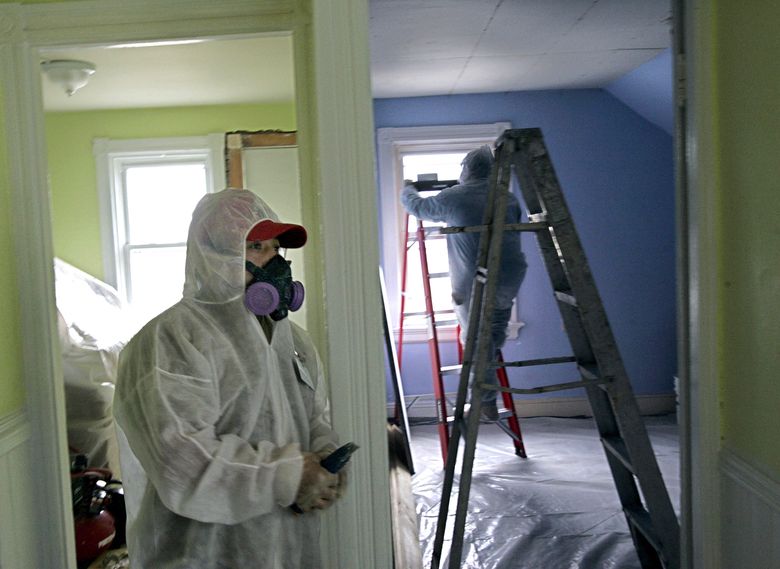 FILE &#8211; Contractors Luis Benitez, foreground, and Jose Diaz, background, clean up lead paint in a contaminated building, Feb. 23, 2006, in Providence, R.I. (AP Photo/Chitose Suzuki)