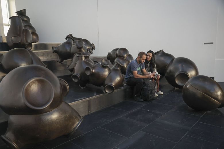 Jed Brown, left, and Kelsey Meyer, right, of Alaska, wait for their connection flight among an art installation called “cloudsandclunkers” by Peter Shelton at Seattle–Tacoma International Airport. (Ivy Ceballo / The Seattle Times)