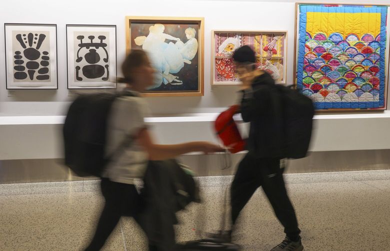 Travelers walk past a gallery display next to the Seattle–Tacoma International Airport’s first all-gender bathroom in SeaTac on Wednesday, October 16, 2024.
228265