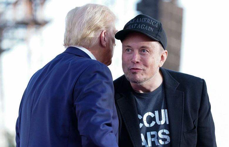 Tech billionaire Elon Musk listens to Donald Trump during a campaign event last month in Butler, Pennsylvania. President-elect Trump announced Tuesday night that Musk will co-chair an outside panel to cut federal spending, known as the Department of Government Efficiency. (MUST CREDIT: Jabin Botsford/The Washington Post)