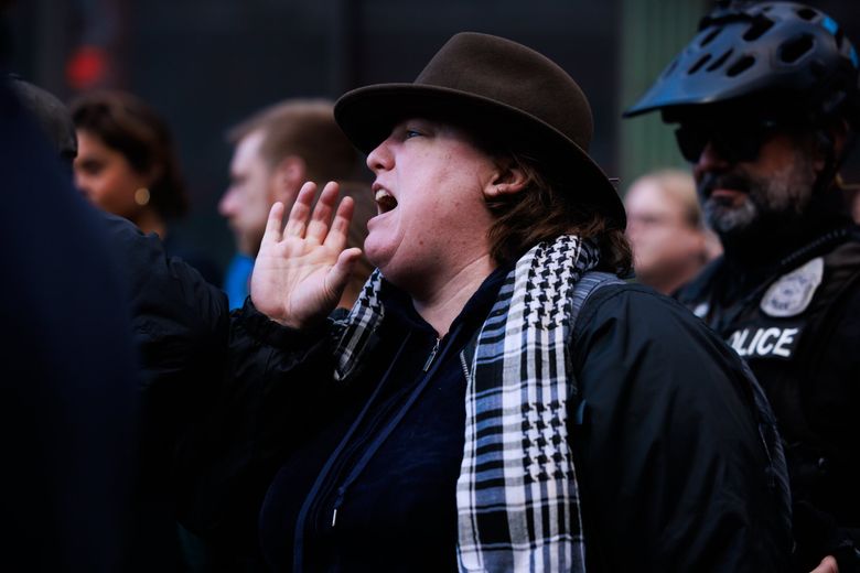 A woman yells &#8220;Stop the sweeps&#8221; at a news conference with Seattle Mayor Bruce Harrell near Pike Place Market in Seattle on Friday. After Harrell handed off the microphone to Jon Scholes, president and CEO of the Downtown Seattle Association, he went to speak with the woman, who eventually left. (Erika Schultz / The Seattle Times)