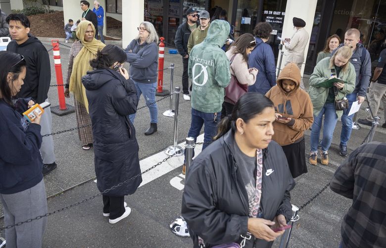 Yulia Sych, top right, looking down, stands with others outside of King County Elections headquarters in Renton and fills out a form so she can become a registered voter Tuesday, November 5, 2024.
An official at the headquarters said they predicted that  82% percent of registered voters would cast their ballots. 228438