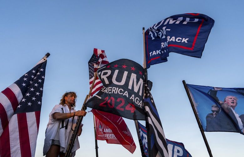 Nikki Fuller, 56, sets up flags on her truck near the Mar-a-Lago estate of President-elect Donald Trump, Monday, Nov. 11, 2024, in Palm Beach, Fla. (AP Photo/Julia Demaree Nikhinson)
