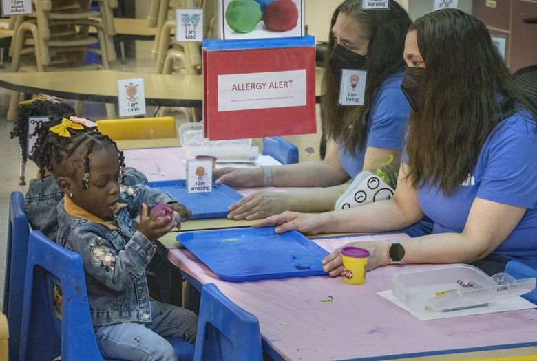 Jenna Carodiskey-Wiebe, assistant teacher with the Early Childhood Education and Assistance Program, right, watches an ECEAP student play with Play-Doh in her classroom at Akin’s Early Learning Center in Auburn on  March 26, 2024. (Ellen M. Banner / The Seattle Times)