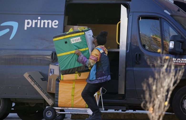 An Amazon Prime delivery person lifts packages while making a stop on Nov. 28, 2023, in Denver. (AP Photo/David Zalubowski) 