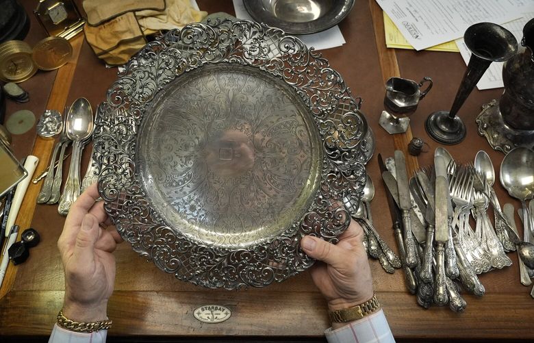 Appraiser Kaja Veilleux looks through a collection of silver items at Thomaston Place Auction Galleries, Tuesday, Nov. 19, 2024, in Thomaston, Maine. (AP Photo/Robert F. Bukaty) 
