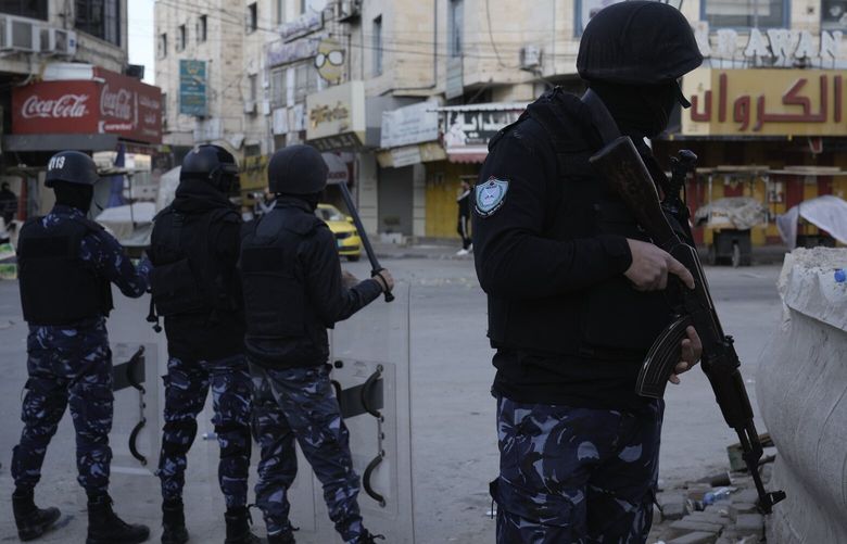 A officer from the Palestinian Authority clutches his gun as Palestinian security forces mount a major raid against militants in the Jenin refugee camp in the Israeli-occupied West Bank, Monday, Dec. 16, 2024.(AP Photo/Majdi Mohammed). MJ107 MJ107