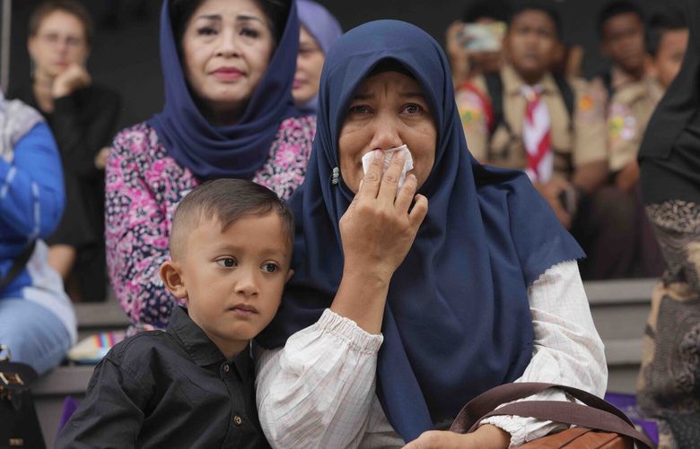 Muslina, a 43-year-old civil servant who is also a tsunami survivor weeps as she and her son Zayyan Firdaus Akmal watch a stage performance depicting the Indian Ocean tsunami in 2004, in Banda Aceh, Indonesia, Saturday, Dec 14, 2024. (AP Photo/Achmad Ibrahim) AI119 AI119