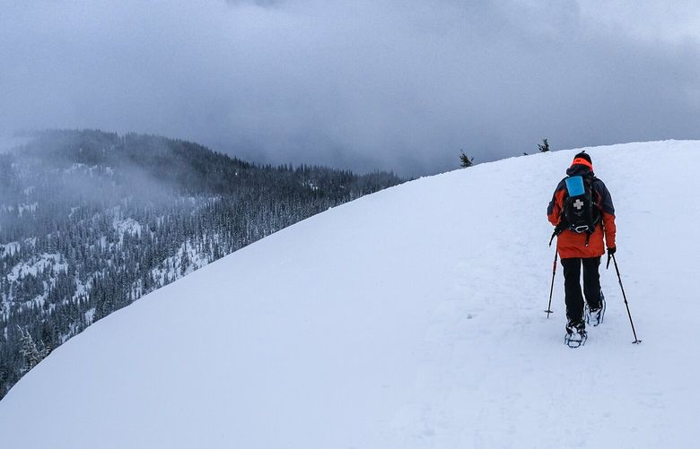 A snowshoer summits a hill while exploring Hurricane Ridge on the Olympic Peninsula.