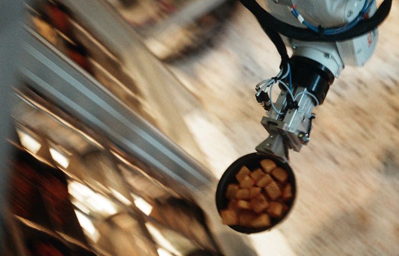 A robotic arm moves prepared food into an oven at Kernel, a new restaurant chain in New York, Dec. 3, 2024. Restaurants are experimenting with automation, but in the kitchen, human labor is hard to replace. (Brian Karlsson/The New York Times)