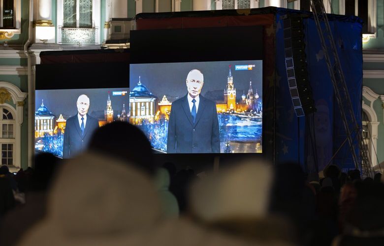 People watch Russian President Vladimir Putin’s New Year’s message a few minutes prior to the New Year at the Palace Square in St. Petersburg, Russia, late Tuesday, Dec. 31, 2024. (AP Photo/Dmitri Lovetsky) XDL108 XDL108