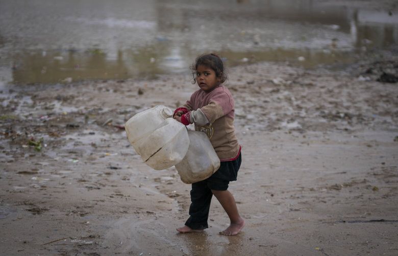 A young girl walks barefoot, carrying empty jerrycans to collect water, after overnight rainfall at the refugee tent camp for displaced Palestinians in Deir al-Balah, central Gaza Strip,, Tuesday, Dec. 31, 2024. (AP Photo/Abdel Kareem Hana) XEM101 XEM101