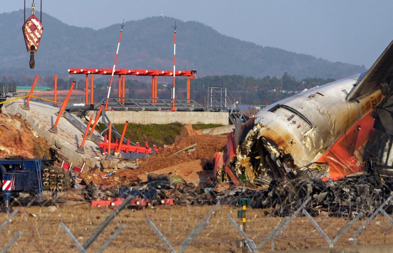 The wreckage of Jeju Air Flight 7C2216 and the structure at the end of the runway that the plane hit, causing it to burst into flames, in Muan, South Korea, on Monday morning, Dec. 30, 2024.  Aviation safety analysts said they expect officials investigating the crash, which killed 179 people, to look into the location and composition of a structure housing an antenna. (Chang W. Lee/The New York Times) XNYT0992 XNYT0992