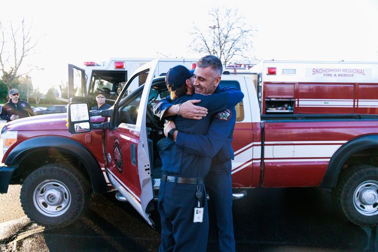 Лейтенант Брайан Киз из Snohomish Regional Fire and Rescue (справа) получает объятия во время сбора пожарных служб округа Снохомиш на учебной территории South County Fire в округе Снохомиш, где они готовятся отправиться в Калифорнию для помощи в борьбе с разрушительными пожарами в среду. (Эрика Шульц / The Seattle Times)