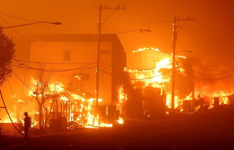 A man stands along Pacific Coast Highway as the Palisades fire burns houses in Malibu on Tuesday, Jan. 7, 2025. (Wally Skalij/Los Angeles Times/TNS) 131777193W 131777193W