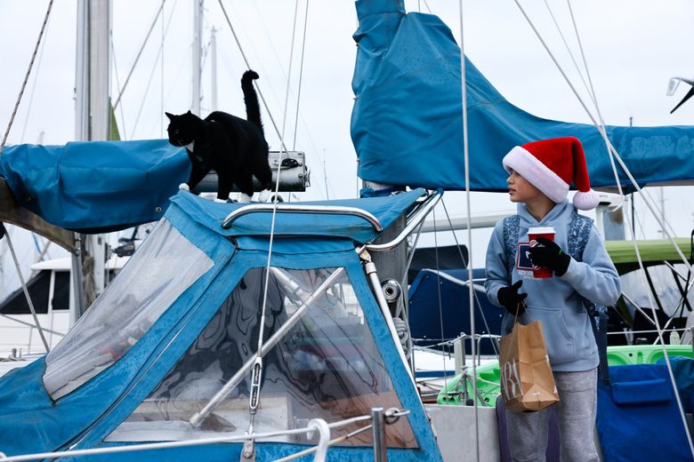 Ze DePaula, 12, says goodbye to one of his family’s cats on his way to school from Shilshole Bay Marina. (Karen Ducey / The Seattle Times)