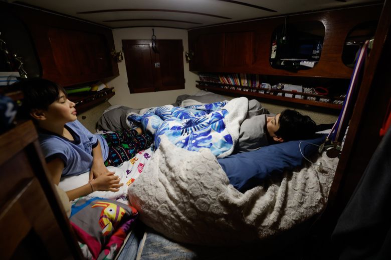 Ze DePaula,12, left, and his brother Joel, 15, slowly rise out of bed to get ready for school. They, their parents and their brother Aiden, 18, moved onto their sailboat in 2018. (Karen Ducey / The Seattle Times)