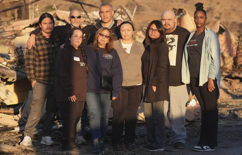 Terraces at Park Marino assisted living facility staff members, back row from left, Juan Pablo Sandoval, Sam Baum and Diversified Healthcare Services President/CEO Adam Khalifa, and front row from left, Sharon Gallego, Maria Quizon, Katherine Castro, Maggie Jay, Edgardo Exia Jr. and Lashawna Thompson pose together amidst the charred remains of the facility on Monday, Jan. 13, 2025, in Pasadena, Calif. (AP Photo/Chris Pizzello) CACP112 CACP112