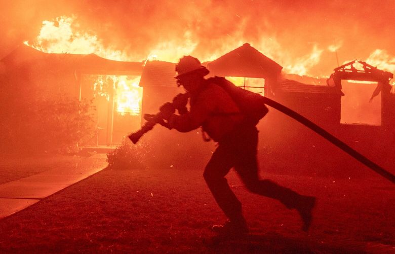 A firefighter battles the Palisades Fire as it burns a structure in the Pacific Palisades neighborhood of Los Angeles, Tuesday, Jan. 7, 2025.