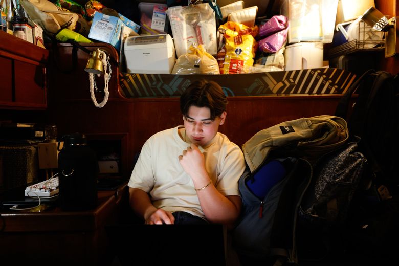 Aiden DePaula, 18, works on his computer from a nook in the living area of his family&#8217;s home, a 53-foot sailboat. (Karen Ducey / The Seattle Times)