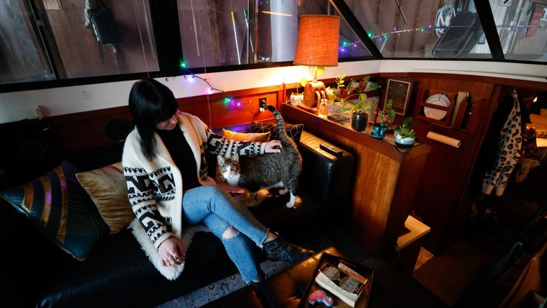 Liberty Bordeaux and her cat Emilio enjoy a cozy living space on her boat, Popcorn, in Sagstad Marina. “I absolutely love it,&#8221; Bordeaux said. &#8220;I have everything that you would have in a big house, but I can see it all, and it&#8217;s way easier to clean.” (Karen Ducey / The Seattle Times)