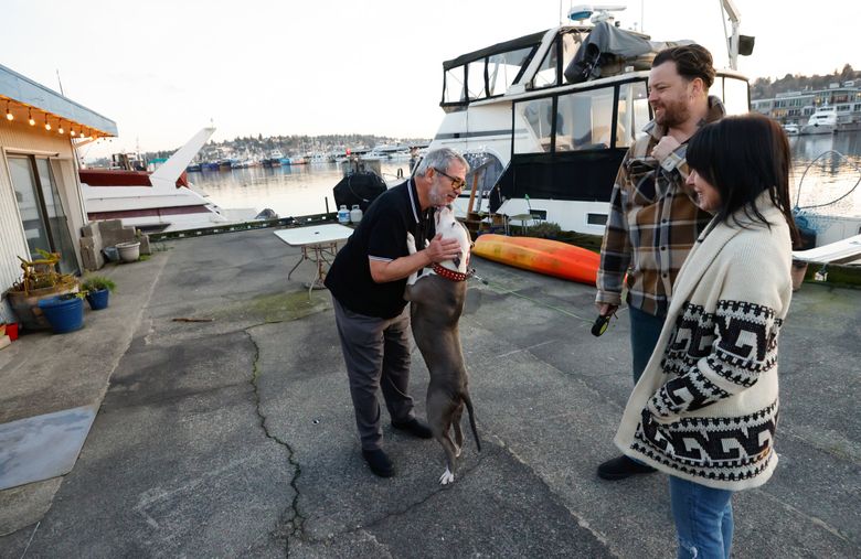 Pea-oui gives a big kiss to Joe Kotler, who lives on the boat in the background, called the Lucky Dog. At right are Ryan Currier (Pea-oui&#8217;s owner) and Liberty Bordeaux. (Karen Ducey / The Seattle Times)