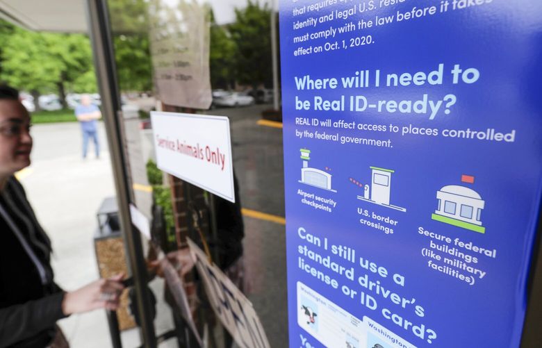 A customer opens the door of a Washington state Dept. of Licensing office in Lacey, Wash., Friday, June 22, 2018 next to a sign providing information about the requirements of Real ID. Some Washington licenses and identification cards will soon be marked with the words “federal limits apply” as the state moves to comply with a federal law that increased rules for identification needed at airports and federal facilities. (AP Photo/Ted S. Warren) WATW204