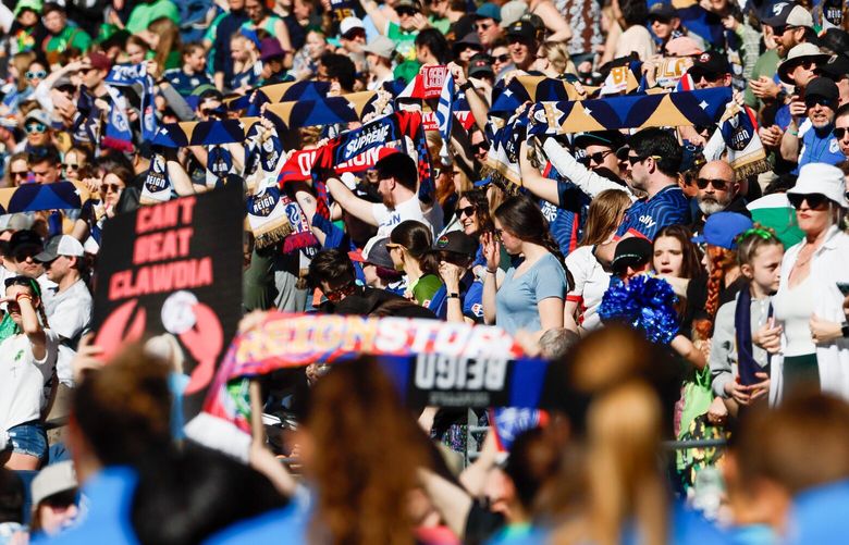 Fans clap and raise their scarves as the Seattle Reign FC and the Washington Spirit walk out onto the pitch for the home opener Sunday, March 17, 2024 in Seattle. 226432