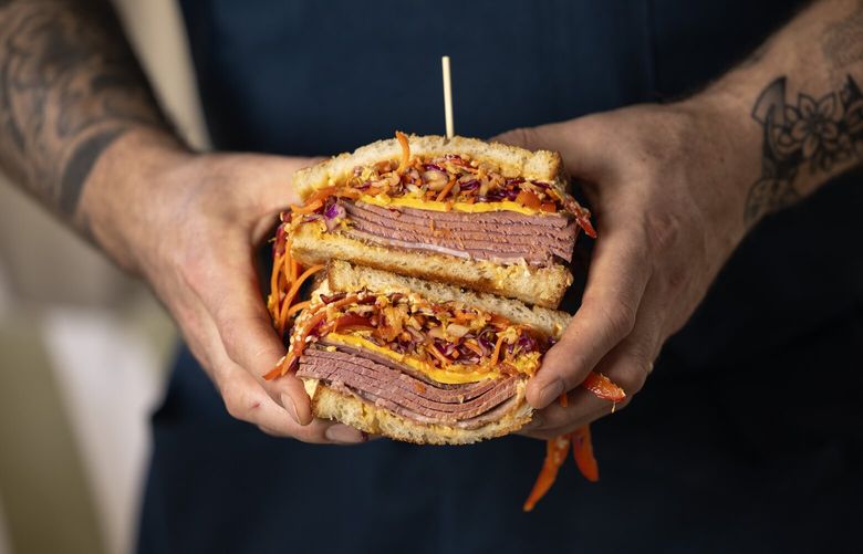 Chef and co-owner of Layers, Avery Hardin, holds his Seoul-ful Seattle Reuben on Wednesday, Dec. 18, 2024, in Seattle.
