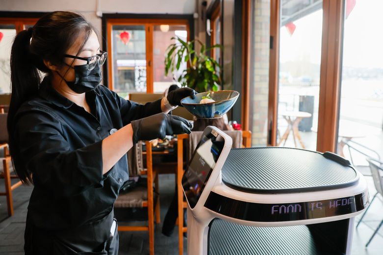 Head server Devina Be takes a bowl of food off a robot at Anchovies &#038; Salt on Monday, Feb. 3. As labor costs rise in Western Washington, local restaurant owners are getting creative to make their bottom lines work. At Anchovies &#038; Salt, a sprawling Vietnamese restaurant on the Renton waterfront, that includes employing robot food runners. (Jennifer Buchanan / The Seattle Times)
