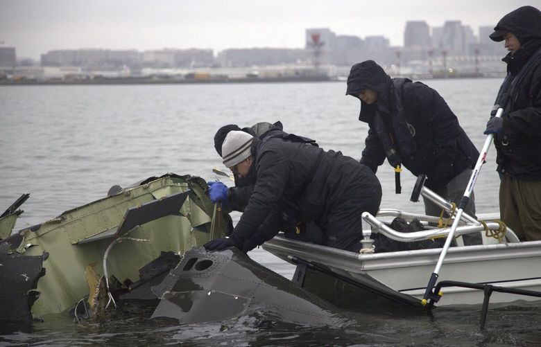 In this undated image provided by the National Transportation Safety Board, NTSB investigators and members of the salvage crew recover wreckage from the Army Black Hawk helicopter that collided with an American Airlines jet Wednesday night, Jan. 29, 2025, near Ronald Reagan Washington National Airport in Arlington, Va. (NTSB via AP) NTS502 NTS502