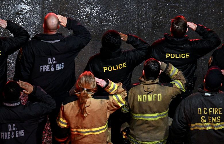 Fire and rescue workers salute as they transfer the remains of one of the U.S. Army soldiers killed when a Black Hawk helicopter collided with an American Airlines flight near Ronald Reagan Washington National Airport in Arlington, Va., on Friday, Jan. 31, 2025. The Army helicopter boasted an experienced crew doing “an unforgiving job.” Friends and relatives are still baffled and mourning their loss.  (Kenny Holston/The New York Times) XNYT0299 XNYT0299
