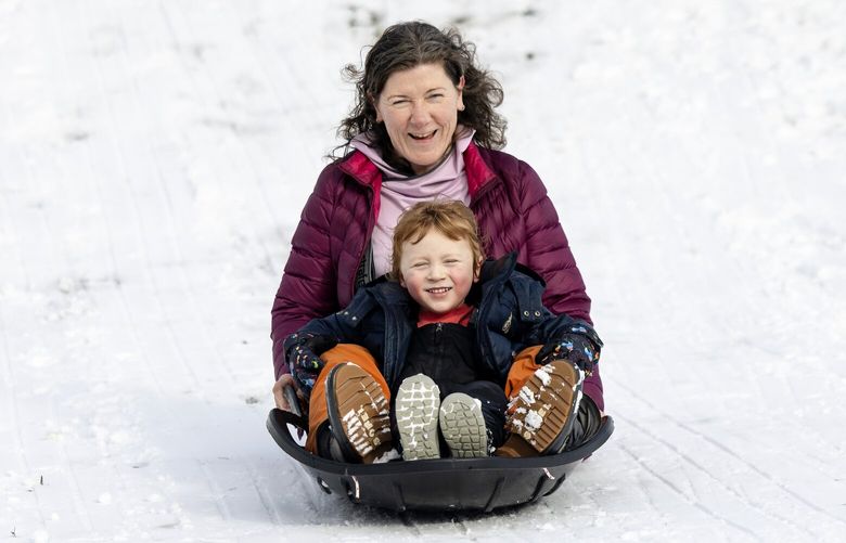 Meghan Palmer sleds down a hill with her son, Jamie Campbell, 5, at Maple Leaf Reservoir Park on Thursday, Feb. 6, 2025, in Seattle.