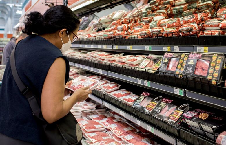 Mai Fee compares the prices of different meats at a grocery store in Vancouver, Wash., on June 14, 2022. She noticed the steep increase in the price of red meat earlier this year. (Celeste Noche/The New York Times)  XNYT123