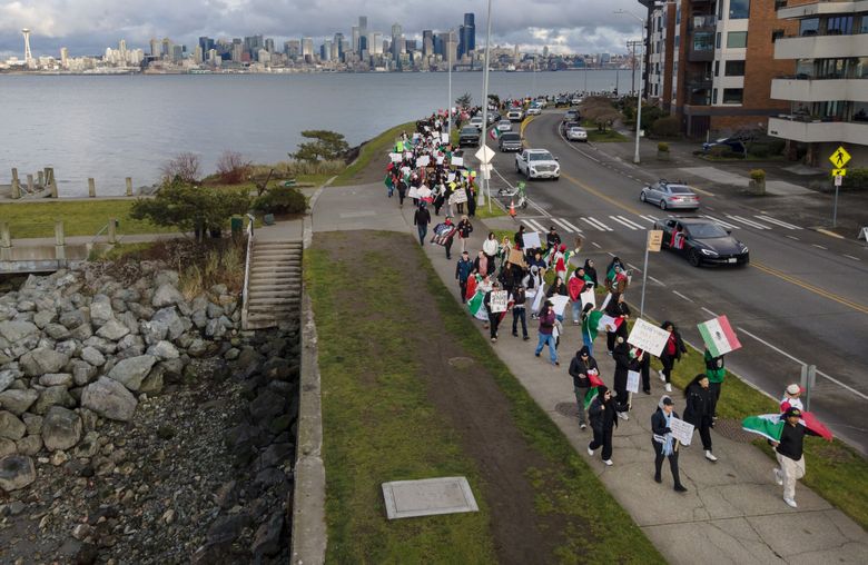 People hold signs and march during a protest against ICE on Sunday in Seattle. King County on Friday joined other so-called &#8220;sanctuary&#8221; jurisdictions in a lawsuit to be filed against the Trump administration, alleging the federal government is illegally commandeering local law enforcement and violating states&#8217; rights. (Nick Wagner / The Seattle Times)