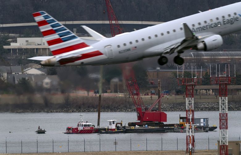 An American Eagle jet passes as rescue and salvage crews work near the wreckage of an American Airlines jet in the Potomac River from Ronald Reagan Washington National Airport, Sunday, Feb. 2, 2025, in Arlington, Va. (AP Photo/Jose Luis Magana) VAJL116 VAJL116