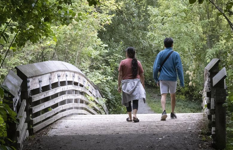 A couple walks over a bridge on Foster Point Trail in the Washington Park Arboretum in Seattle Monday, June 19, 2023.  Rain is predicted for Tuesday but the rest of the week is expected to be sunny and in the 70â€™s. 224226