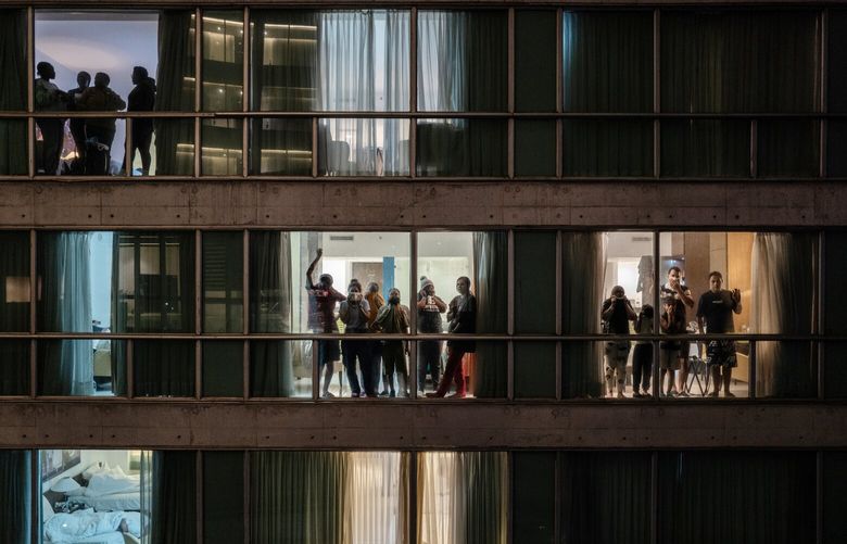 People deported from the U.S., including some from Asian, Middle Eastern and African countries, stand by windows inside the Decapolis Hotel in Panama City, where they are being held, Feb. 15, 2025. U.S. officials are flying hundreds of people who can’t easily be deported to Panama, which President Donald Trump has pressured by threatening to take over the Panama Canal. (Federico Rios Escobar/The New York Times) XNYT0865 XNYT0865