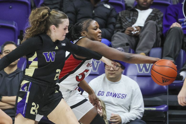 Washington guard Elle Ladine and Rutgers  center Chyna Cornwell chase down a loose ball Thursday, Feb. 20, 2025 in Seattle. (Kevin Clark / The Seattle Times)