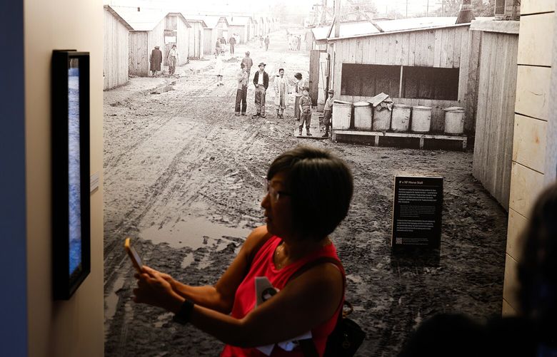 Tina Bean, center, and Kristin Martin, right, from the Blaine Memorial United Methodist Church in Seattle photograph a list of people being thanked in The Remembrance Gallery, at the State Fair in Puyallup on Friday, August 30, 2024. Behind them is a photo of the Puyallup Assembly Center that was located on these fairgrounds during WWII. More than 7,500 people were incarerated here before being transported to incarceration camps in the US interior.