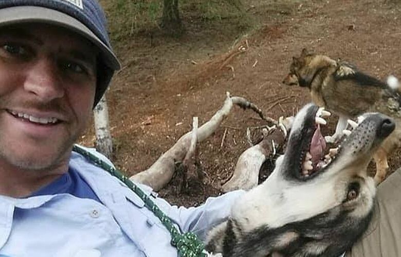 This undated photo shows Mitch Flanigan petting two now-retired sled dogs at Denali National Park and Preserve in Alaska. Flanagan in December 2024 accepted a full-time ranger position working with the sled dog team, but was a probationary worker fired by the U.S. government Feb. 14, 2025. (Mitch Flanigan via AP) AK505 AK505