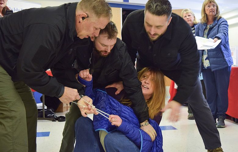 Employees of a security firm, LEAR Asset Management, drag Post Falls resident Teresa Borrenpohl out of a town hall meeting on Saturday, Feb. 22, 2025, in Post Falls, Idaho. (Hailey Hill/Coeur D’Alene Press via AP) IDCOE101 IDCOE101