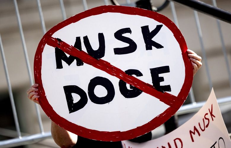 A demonstrator holds a sign during a rally to protest President Donald Trump and Elon Musk policies Feb. 17, 2025, in Los Angeles. (AP Photo/Etienne Laurent, File) WX202 WX202