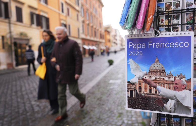 Pedestrians pass a shop selling Pope Francis souvenirs in Rome, Italy Tuesday, Feb. 25, 2025. (AP Photo/Kirsty Wigglesworth) LKW102 LKW102