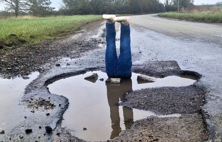 James Coxall placed a pair of jeans, stuffed with wood and old shirts, in a pothole on Haverhill Road in Castle Camps, an English village. MUST CREDIT: James Coxall