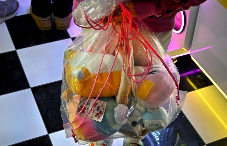 Genevieve Olson, 8, holds her bag of winnings at the Meow Claw arcade in Rockville, Maryland, on Jan. 25. She came to the arcade with her family to celebrate her dad’s birthday. MUST CREDIT: Michael S. Williamson/The Washington Post