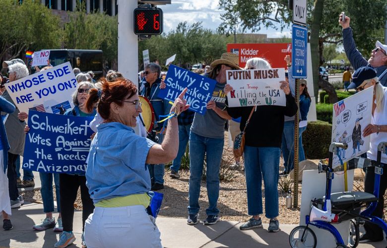 Lucy Marshall, a volunteer for Maricopa Democrats, waves at protestors gathered outside of Rep. David Schweikert’s (R-AZ) offices in Scottsdale, Ariz., March 3, 2025. With President Donald Trump set to address a joint session of Congress on Tuesday, many voters in Arizona’s divided First Congressional District remain hopeful for his new term, even amid partisan rancor. (Ash Ponders/The New York Times) XNYT0303 XNYT0303