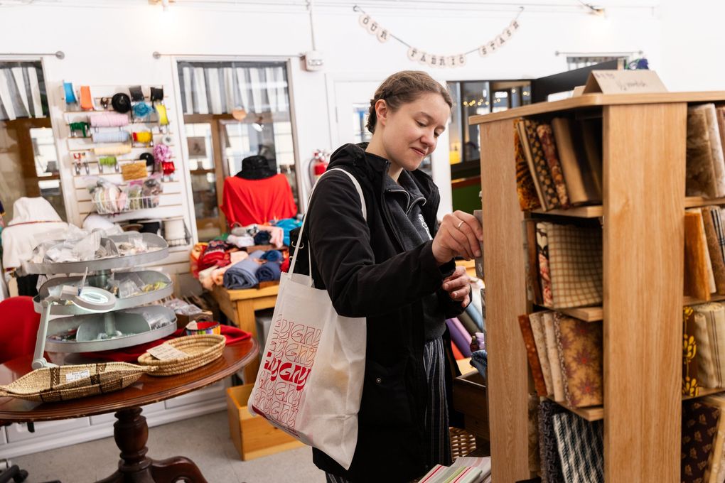 Emily McKinney, from Spokane, browses inside Our Fabric Stash, a fabric consignment shop inside Pike Place Market in Seattle. (Erika Schultz / The Seattle Times)