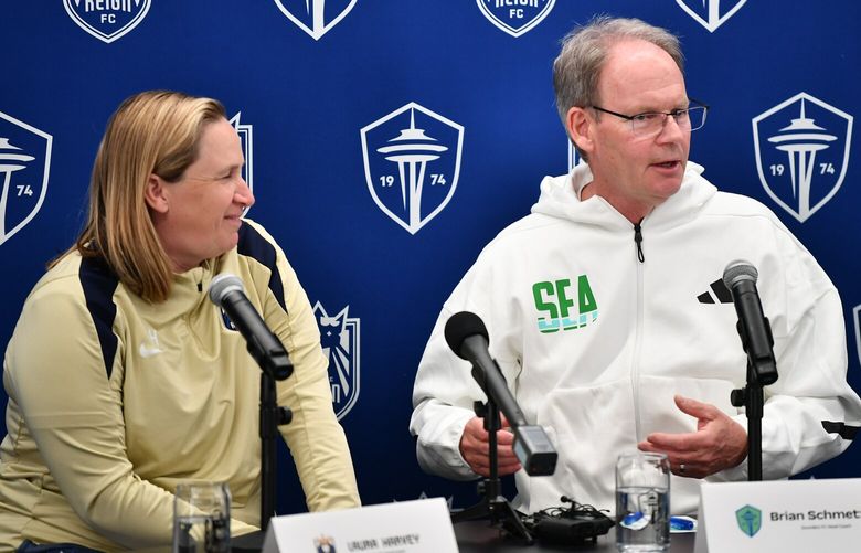 Reign FC coach Laura Harvey looks on as Seattle Sounders FC coach Brian Schmetzer speaks during a press conference discussing the organization’s renewed focus on fan engagement and development, March 7, 2025 in Renton.