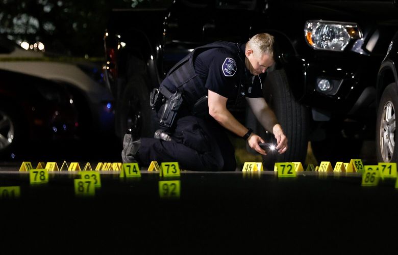 A Seattle Police officer takes a photo as he investigates a shooting in the parking lot of the former King Donut on Rainier Ave S. Friday, July 28, 2023 in Seattle.